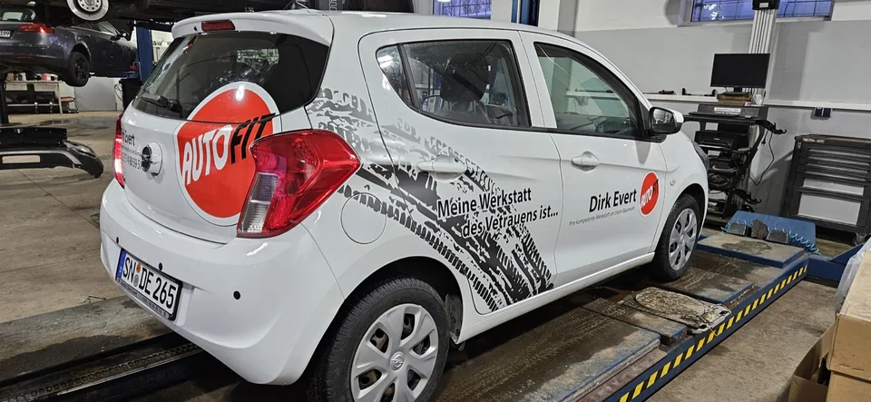 Weißer Kleinwagen mit rotem AutoFIT-Logo und schwarzer Reifenprofil-Grafik