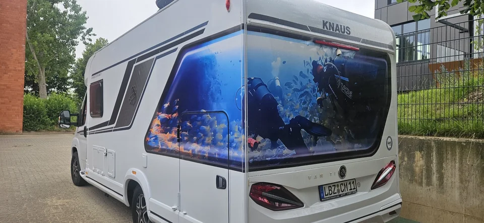Wohnmobil mit großflächigem Unterwassermotiv und Taucher am Heck