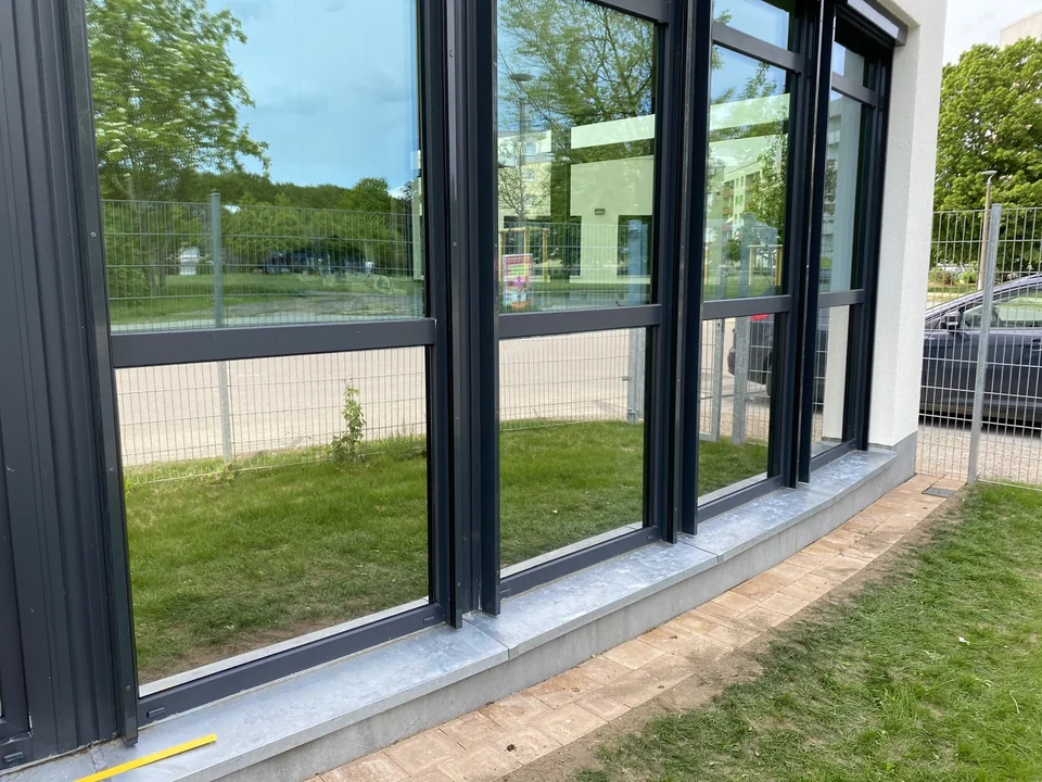 Spiegelnde Glasfront mit dunklen Fensterrahmen